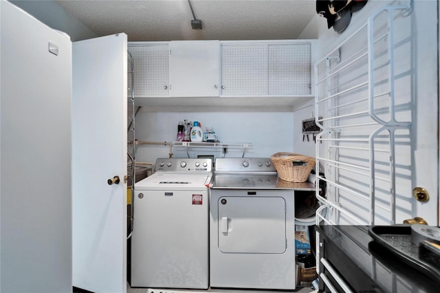 clothes washing area featuring a textured ceiling, separate washer and dryer, and cabinets