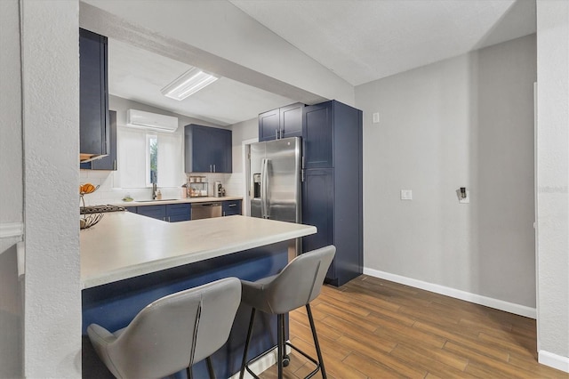 kitchen featuring lofted ceiling, backsplash, kitchen peninsula, blue cabinetry, and a breakfast bar area