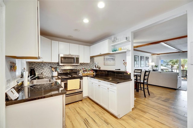 kitchen with white cabinetry, light wood-type flooring, kitchen peninsula, stainless steel appliances, and decorative backsplash