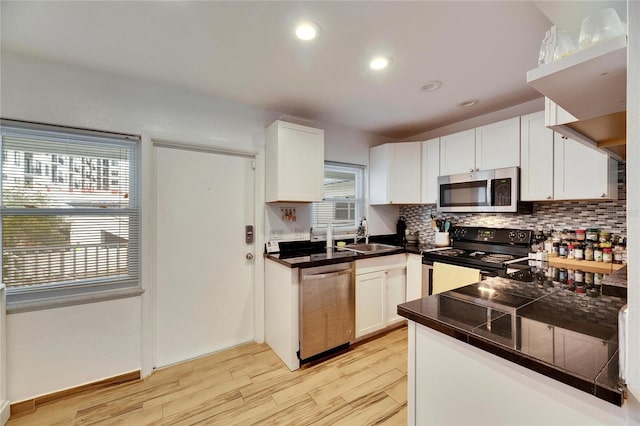 kitchen featuring sink, white cabinetry, stainless steel appliances, light hardwood / wood-style floors, and decorative backsplash