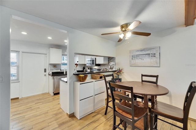 kitchen with light hardwood / wood-style flooring, kitchen peninsula, white cabinets, and appliances with stainless steel finishes