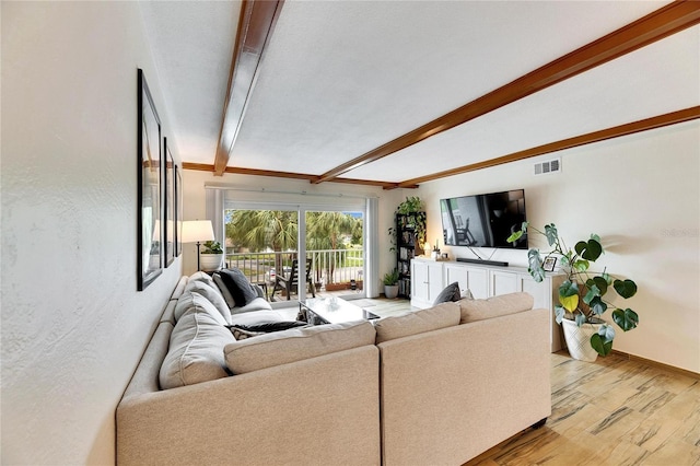 living room featuring beamed ceiling and light hardwood / wood-style floors