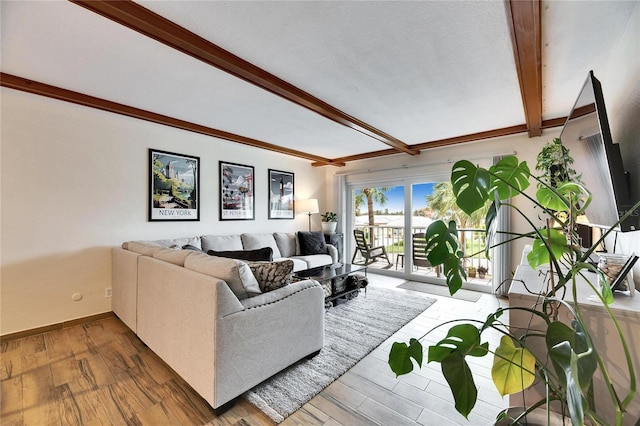 living room with a textured ceiling, beam ceiling, and light hardwood / wood-style flooring