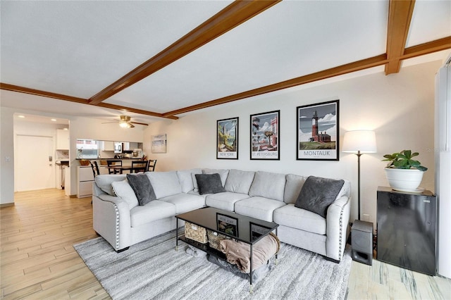 living room with beamed ceiling, ceiling fan, and light hardwood / wood-style flooring