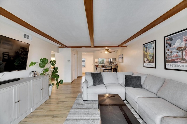 living room featuring beamed ceiling and light hardwood / wood-style floors