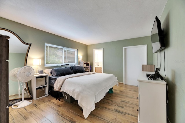 bedroom featuring light hardwood / wood-style floors, a textured ceiling, and ensuite bathroom