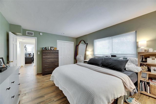 bedroom featuring light hardwood / wood-style flooring, a closet, and a textured ceiling