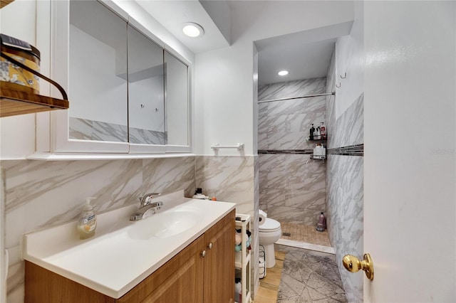 bathroom featuring vanity, tile walls, toilet, and tiled shower