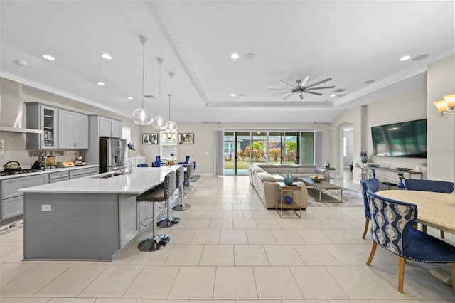 kitchen with a breakfast bar area, stainless steel fridge with ice dispenser, a raised ceiling, pendant lighting, and a large island