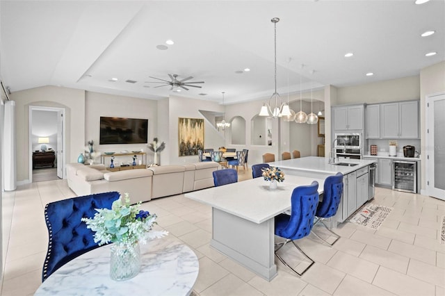 kitchen with sink, decorative light fixtures, a kitchen breakfast bar, an island with sink, and beverage cooler