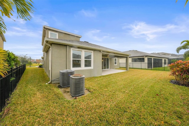 back of property with central AC, a patio, and a lawn