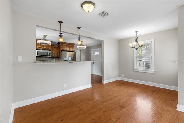 kitchen with backsplash, dark hardwood / wood-style floors, pendant lighting, kitchen peninsula, and appliances with stainless steel finishes