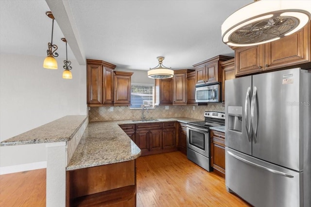 kitchen featuring a kitchen bar, kitchen peninsula, stainless steel appliances, backsplash, and sink