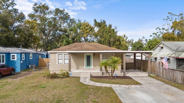 view of front of house with covered porch, a front yard, central AC unit, and a carport