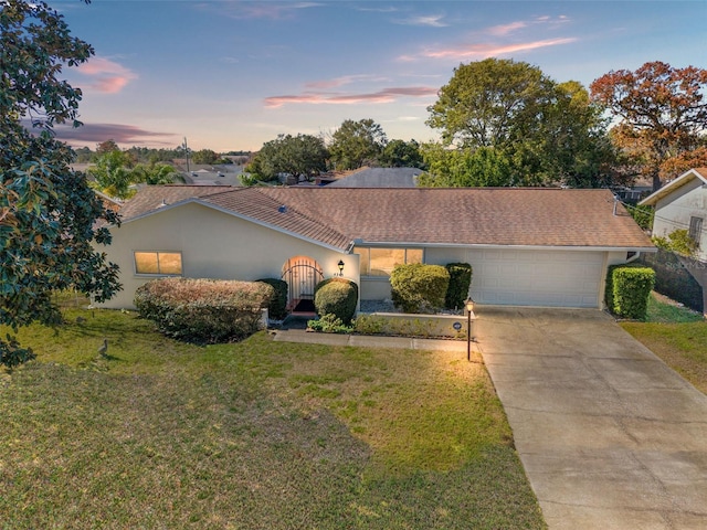 single story home with a garage and a lawn