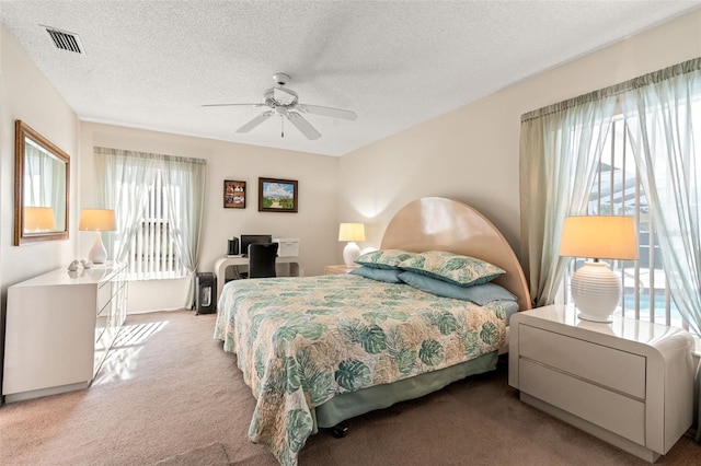 bedroom with light carpet, ceiling fan, and a textured ceiling