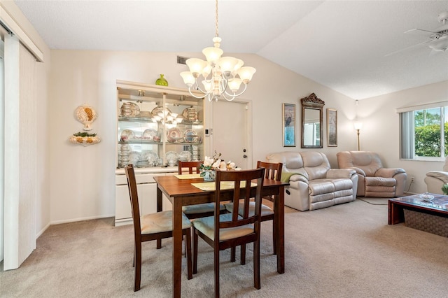 carpeted dining room with ceiling fan with notable chandelier and vaulted ceiling