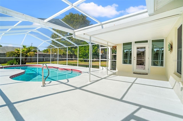 view of swimming pool with glass enclosure, a patio area, and a lawn