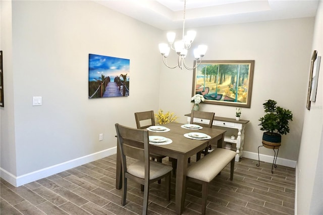 dining space featuring baseboards, an inviting chandelier, a raised ceiling, and wood tiled floor