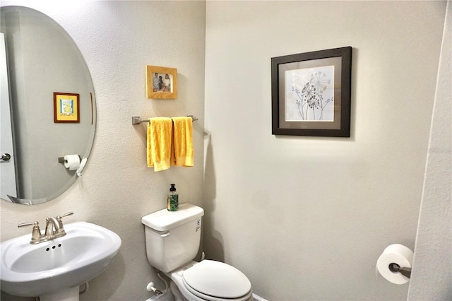 bathroom featuring baseboards, a sink, and toilet