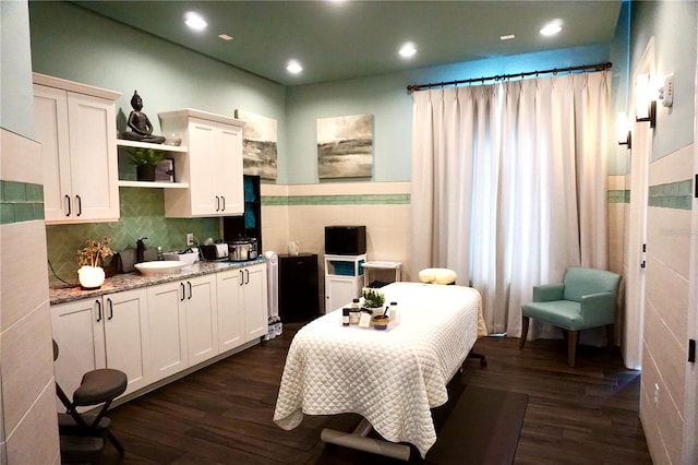 bedroom featuring recessed lighting, dark wood finished floors, tile walls, and a sink