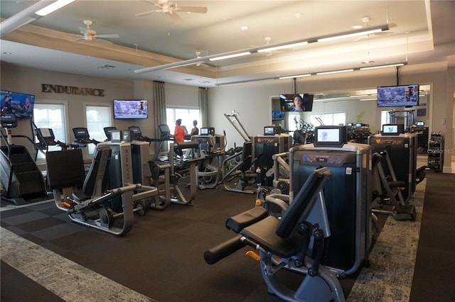 exercise room with ceiling fan and a tray ceiling