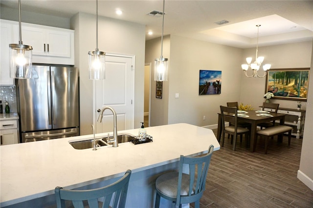 kitchen featuring hanging light fixtures, wood finish floors, a sink, and freestanding refrigerator