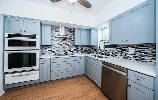 kitchen featuring sink, black electric stovetop, stainless steel dishwasher, light hardwood / wood-style floors, and wall chimney range hood