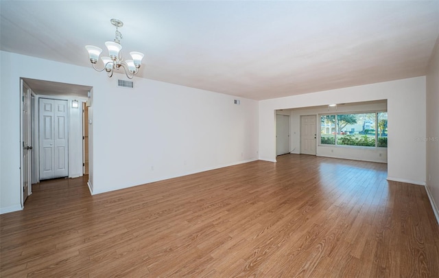 spare room with hardwood / wood-style flooring and a chandelier