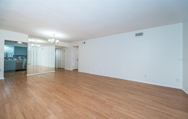 unfurnished living room featuring a chandelier and light wood-type flooring