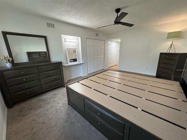 carpeted bedroom featuring ceiling fan and a textured ceiling