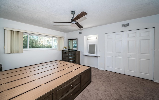 carpeted bedroom with ceiling fan, a textured ceiling, and a closet