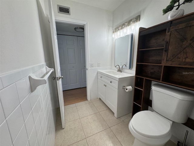 bathroom with tile walls, vanity, tile patterned floors, and toilet