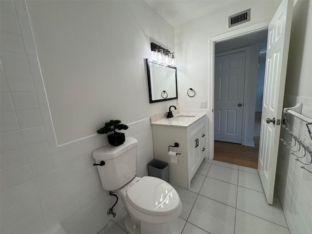 bathroom with tile walls, vanity, tile patterned flooring, and toilet