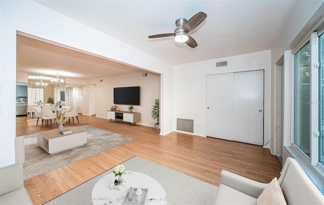 living room with hardwood / wood-style floors and ceiling fan with notable chandelier