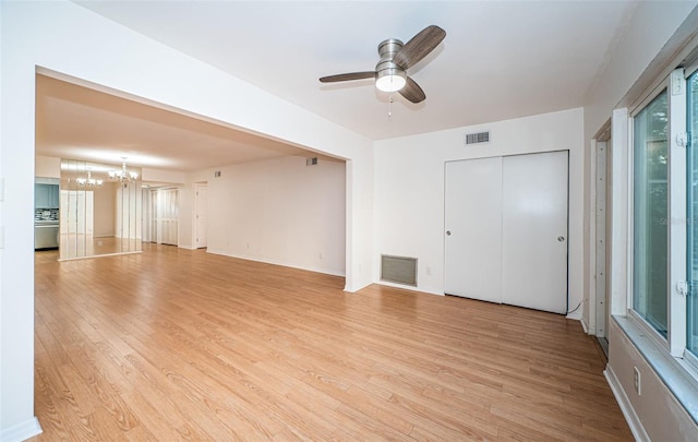 unfurnished living room with ceiling fan with notable chandelier and light wood-type flooring