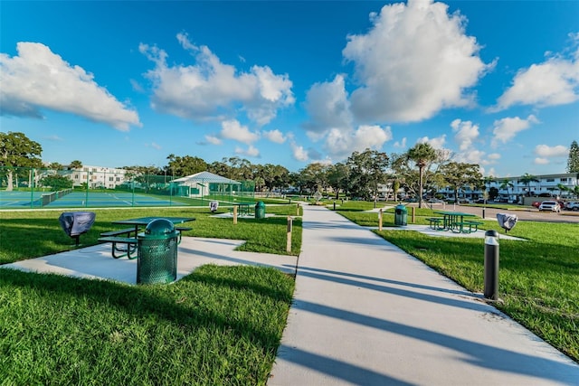 view of community featuring tennis court and a lawn