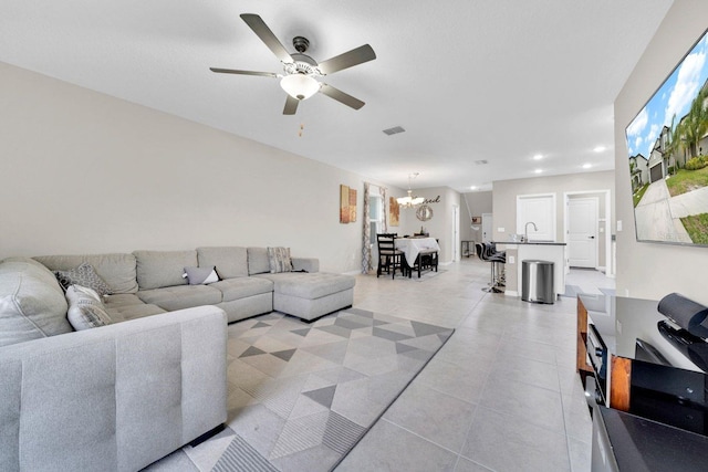 tiled living room with ceiling fan with notable chandelier and sink