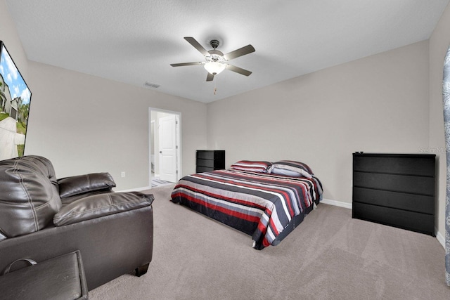 bedroom featuring ceiling fan, light colored carpet, and a textured ceiling