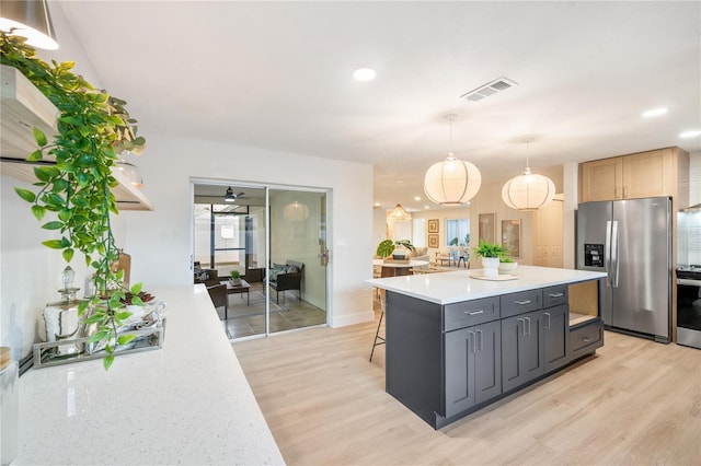 kitchen with appliances with stainless steel finishes, a kitchen island, a kitchen breakfast bar, hanging light fixtures, and light wood-type flooring