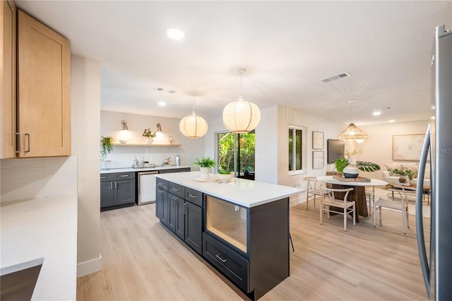 kitchen featuring decorative light fixtures, appliances with stainless steel finishes, light brown cabinets, and light hardwood / wood-style flooring