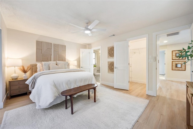 bedroom featuring a spacious closet, ceiling fan, connected bathroom, light wood-type flooring, and a closet