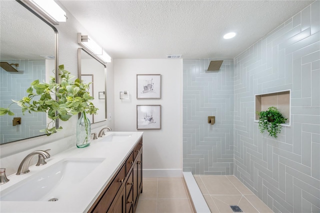 bathroom with vanity, tiled shower, tile patterned floors, and a textured ceiling