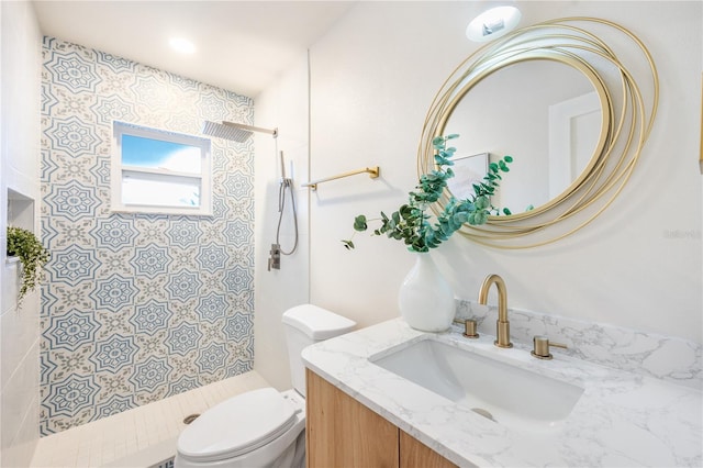 bathroom featuring toilet, vanity, and tiled shower