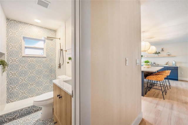 bathroom featuring hardwood / wood-style floors, toilet, walk in shower, and vanity