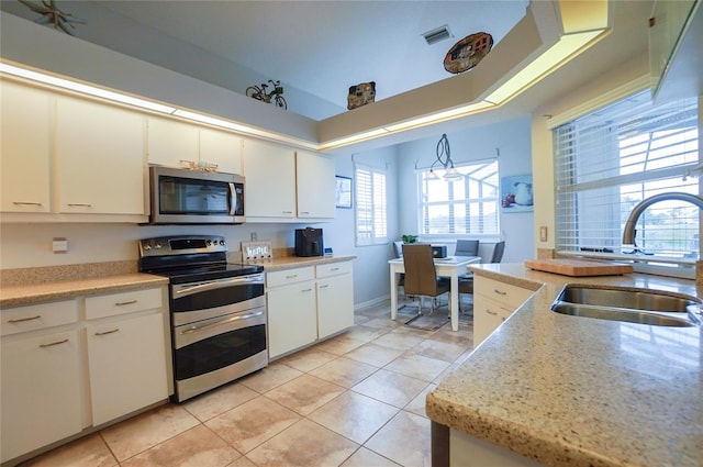 kitchen with light tile patterned floors, appliances with stainless steel finishes, white cabinets, and sink