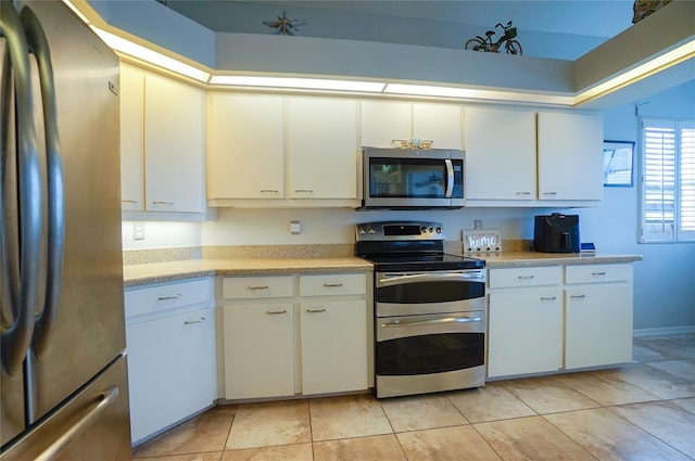 kitchen with light tile patterned flooring, stainless steel appliances, and white cabinetry