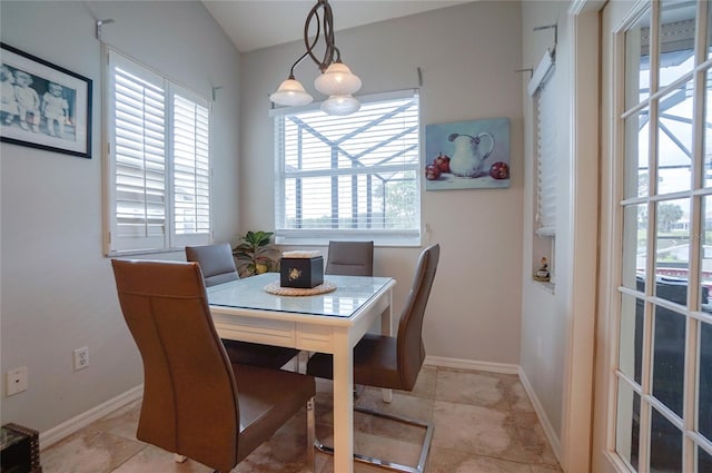 tiled dining room with an inviting chandelier and a healthy amount of sunlight