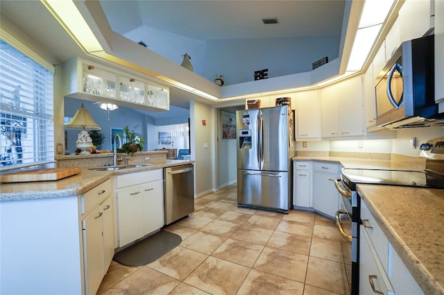 kitchen with white cabinets, vaulted ceiling, appliances with stainless steel finishes, and sink