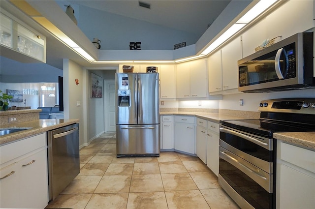 kitchen featuring white cabinetry, lofted ceiling, stainless steel appliances, and light tile patterned flooring